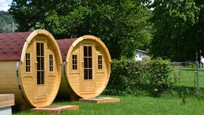 Two wooden barrel-shaped cabins with arched doorways, numbered 20 and 21, set in a grassy area with a fence and trees in the background. - NATURAMA Beilngries (Beilngries)