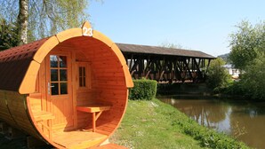 A wooden boat-shaped cabin with a number 23 sign, a small table, and a bench. - NATURAMA Beilngries (Beilngries)