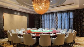 A conference room with a round table, chairs, and a chandelier.