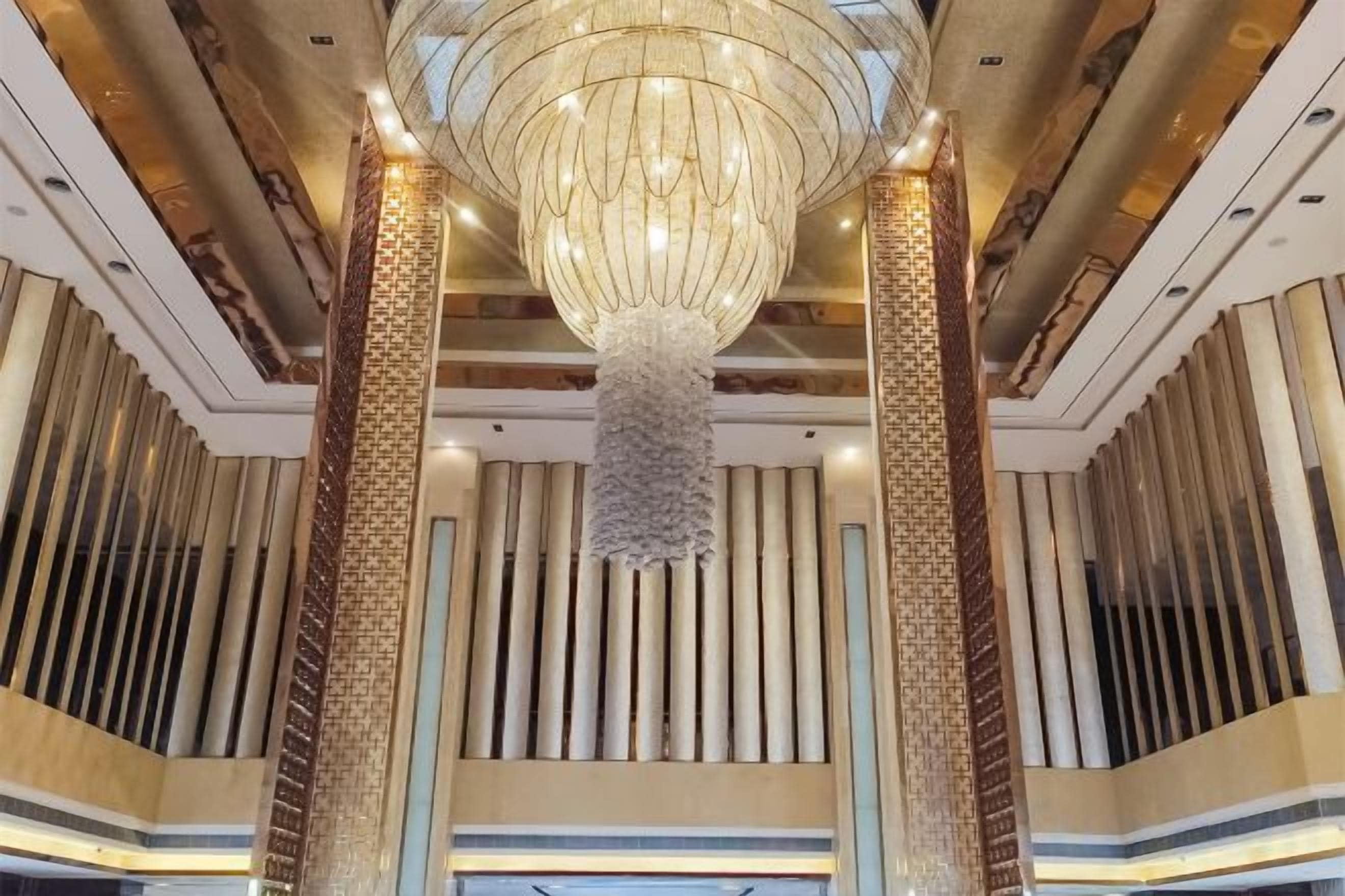 Un hall imponente con un gran candelabro, altas columnas y un diseño moderno.