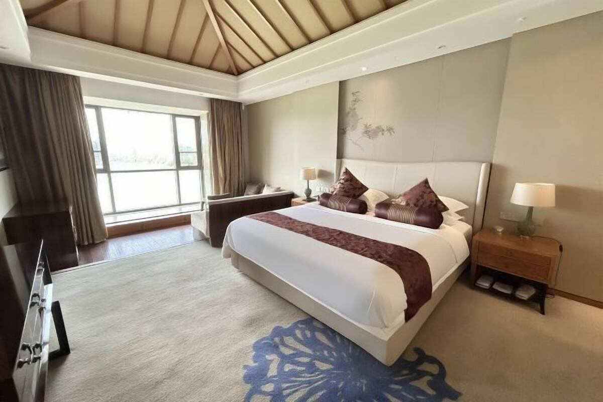 Une chambre d’hôtel avec un grand lit, des tables de chevet, un bureau et une vue sur l’extérieur.