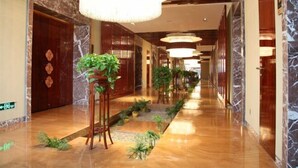 A hotel corridor with marble flooring, wooden doors, and hanging chandeliers. - Shengyuan International Hotel (ZIBO)