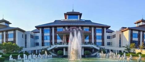 A hotel with a central fountain, a covered entrance, and a symmetrical facade.