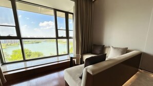 A room with a large window, a sofa, and a small table. - Shengyuan International Hotel (ZIBO)