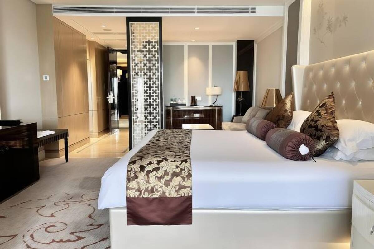 Une chambre d’hôtel avec un grand lit, un bureau, une chaise et une armoire.