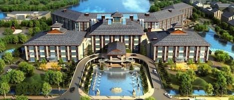 Un hotel de varios pisos con un patio central, piscina y vistas al río.