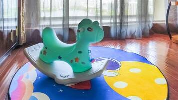 Ein grünes Schaukelpferd auf einer bunten Matte mit Mond- und Sterndruck.