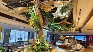 A hotel lobby with a central decorative tree, buffet area with various food items, and seating arrangements. - Shengyuan International Hotel (ZIBO)