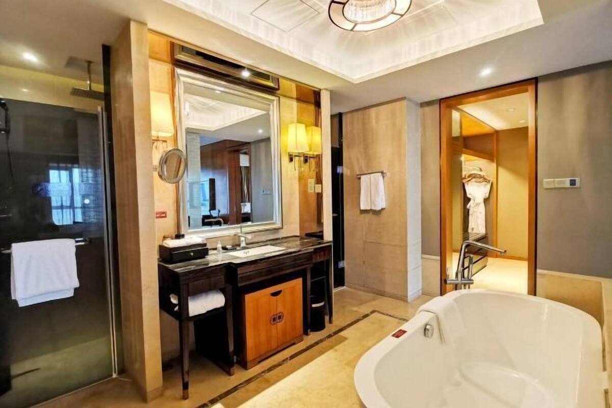 Une salle de bain moderne avec un grand miroir, une baignoire et un meuble-lavabo.