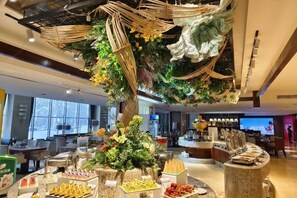 Una hall d'albergo con un albero decorativo al centro, zone relax e una reception.