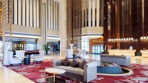 A spacious lobby with a red carpet, modern furniture, and a reception desk. - Shengyuan International Hotel (ZIBO)