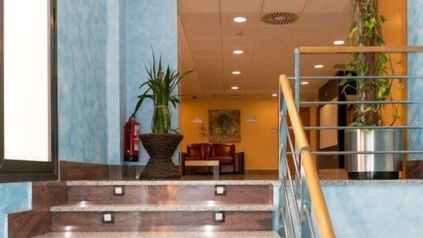 A hotel lobby with a marble staircase, a reception desk, and a plant. - Andamur San Roman (San Millan)