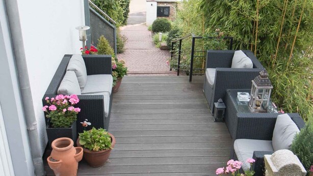A wooden deck with outdoor seating and potted plants. - Hotel Brunnenhof (Hanau)