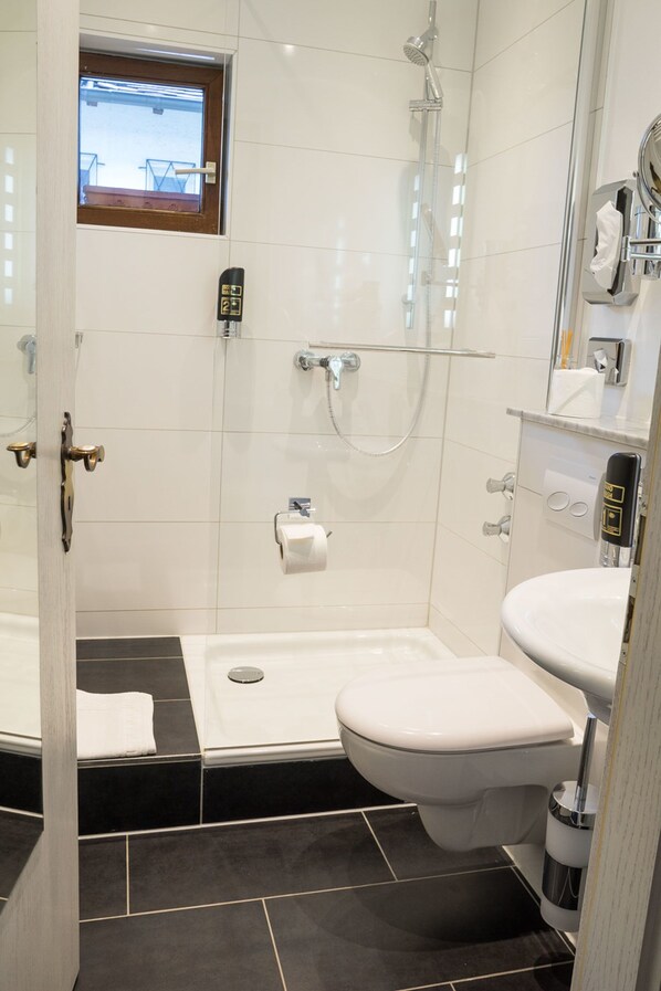 A modern bathroom with a shower, toilet, and sink. - Hotel Brunnenhof (Hanau)