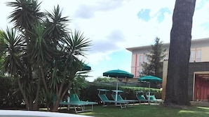 Un jacuzzi con piscina, palmeras y un edificio con puerta roja al fondo.