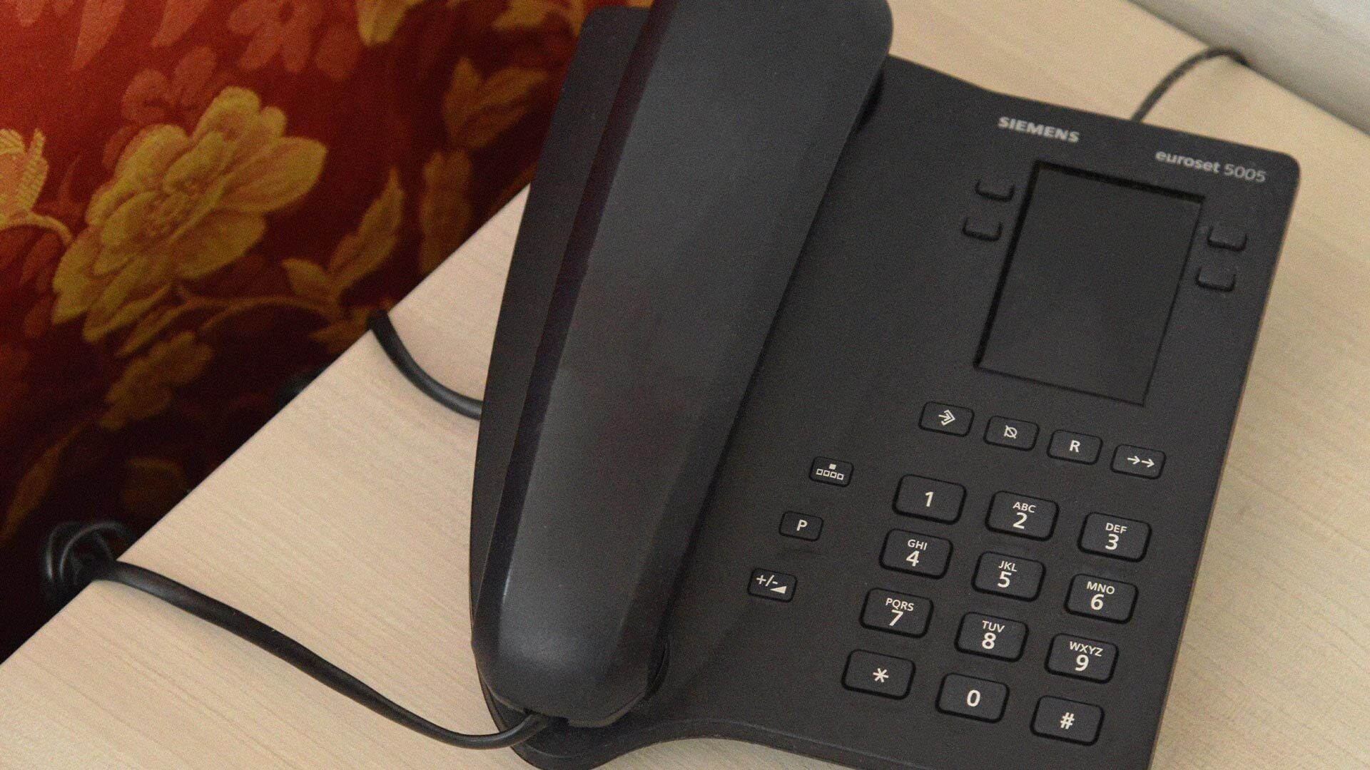 Un teléfono Siemens euroset 5005 negro con teclado y una pantalla pequeña, conectado por un cable.