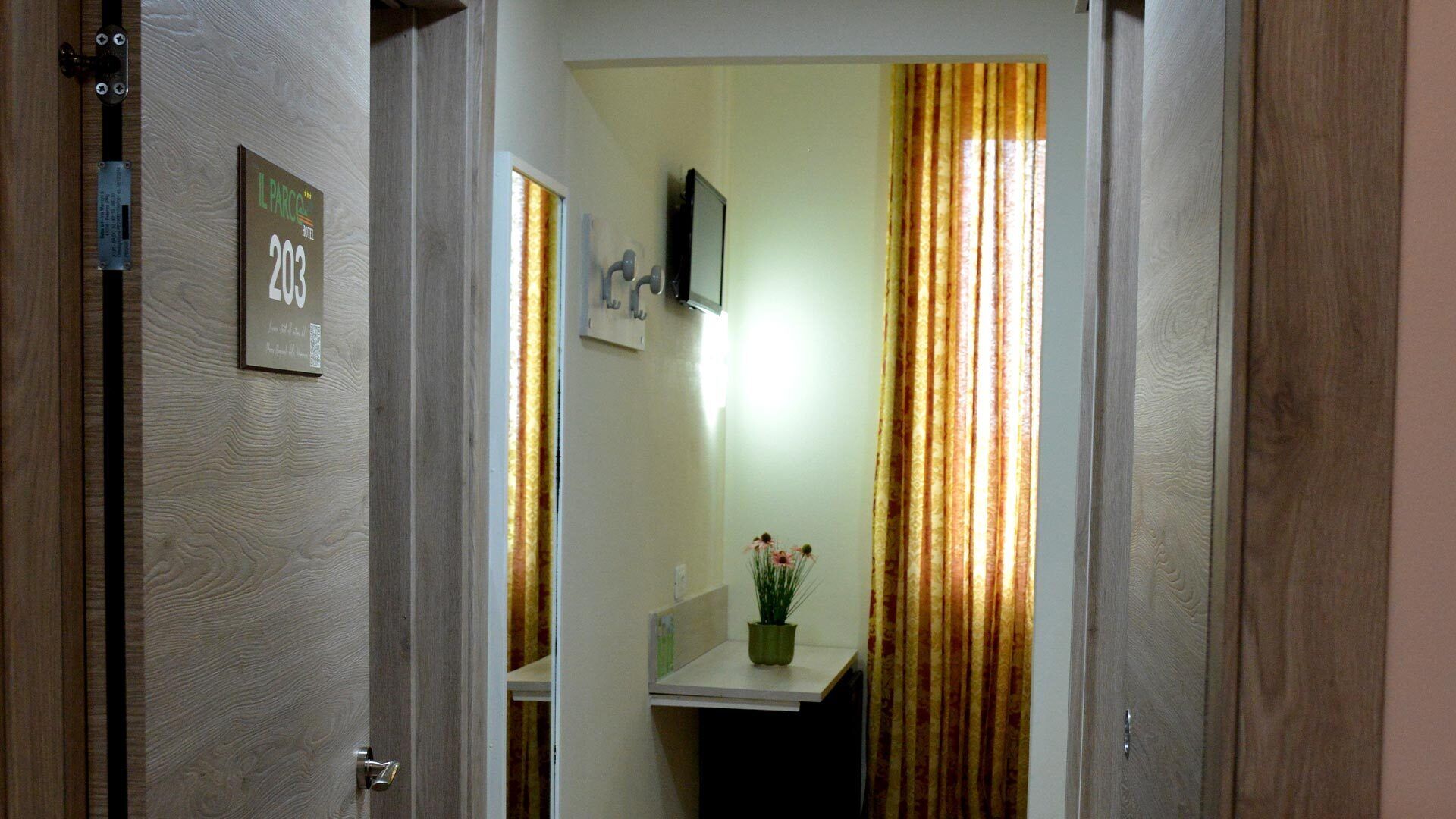 A narrow hallway with a wooden door labeled "23" and a small plant on a shelf.