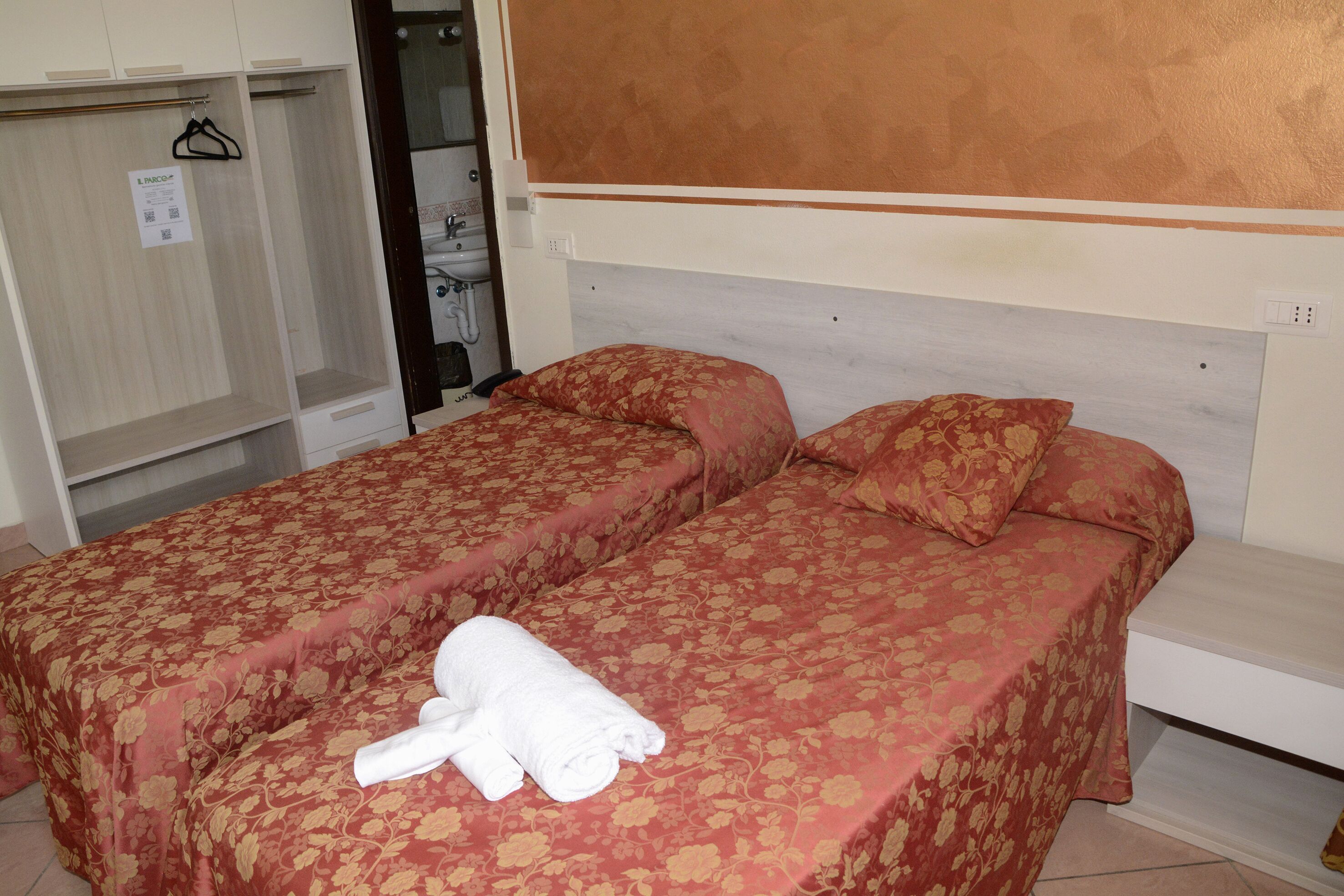 Une chambre d’hôtel avec deux lits, une armoire et une salle de bain visible.