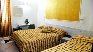 Une chambre d’hôtel avec deux lits, un bureau, une chaise, une petite plante en pot et une grande fenêtre.