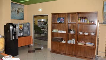 A hotel lobby with a buffet area, a coffee machine, and a large wooden cabinet with various items.