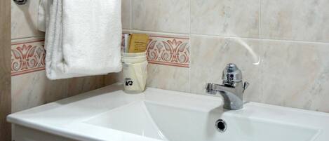 A bathroom with a white sink, a silver faucet, and a towel hanging on a metal towel rack.