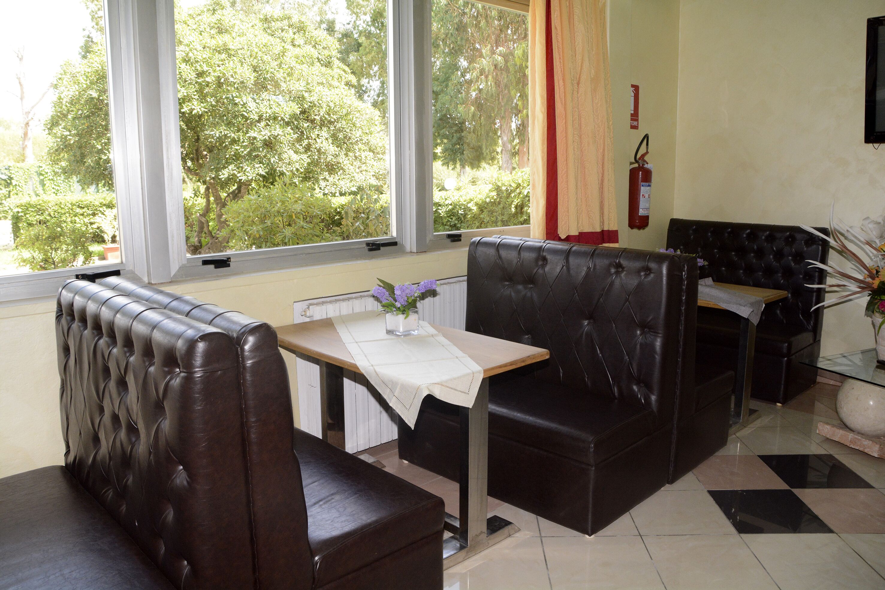 Un comedor con asientos de cuero, una mesa con un jarrón de flores y un extintor en la pared.