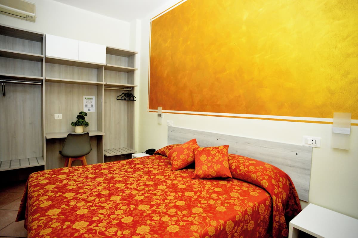 Une chambre d’hôtel avec un lit, un bureau et une armoire.