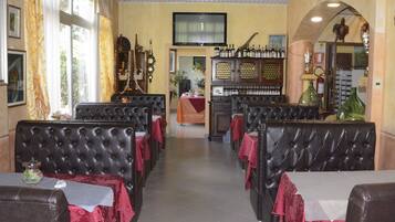 Un ristorante con sedute in pelle, un'area bar con bottiglie e un televisore appeso al muro.
