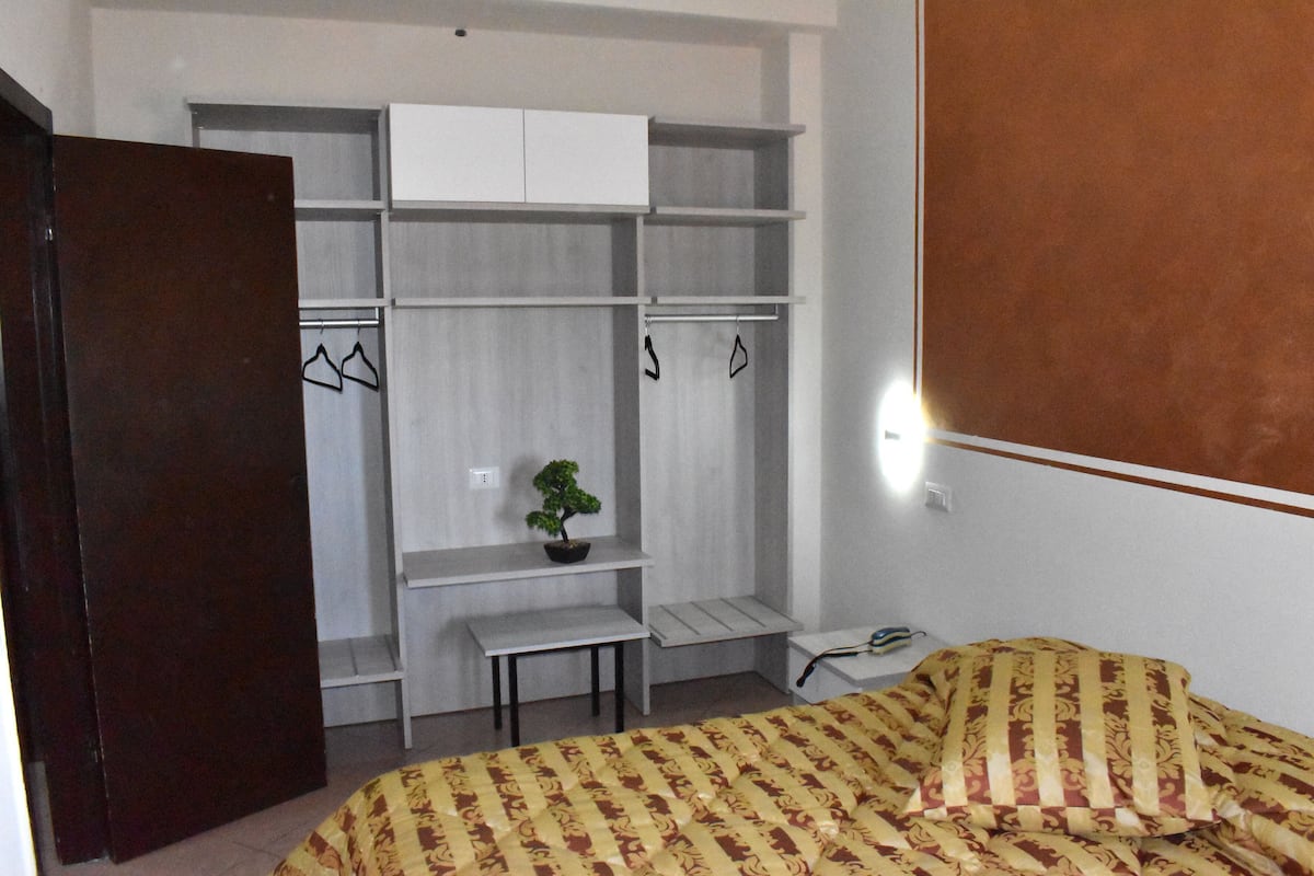 Une chambre à coucher avec un lit, une armoire, une petite table et une plante en pot.