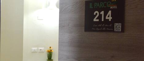 Habitación de hotel con una pared de madera, un letrero con el número 214 y un código QR.