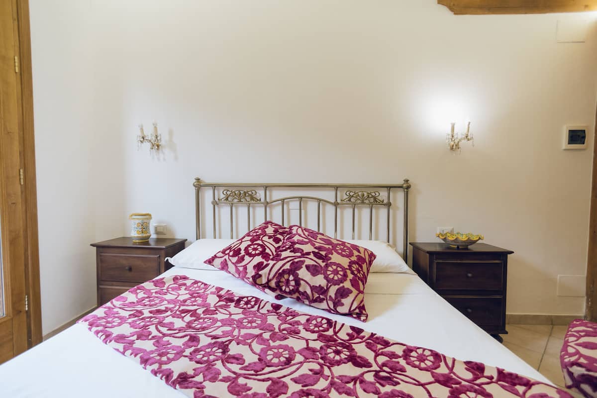 A bedroom with a bed, two nightstands, a wooden headboard, and a floral-patterned bedspread.