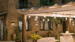 A stone building with a covered outdoor seating area, potted plants, and string lights. - Agriresort Leano (Piazza Armerina)