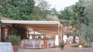 An outdoor dining area with tables and chairs under a canopy, surrounded by greenery and trees. - Agriresort Leano (Piazza Armerina)