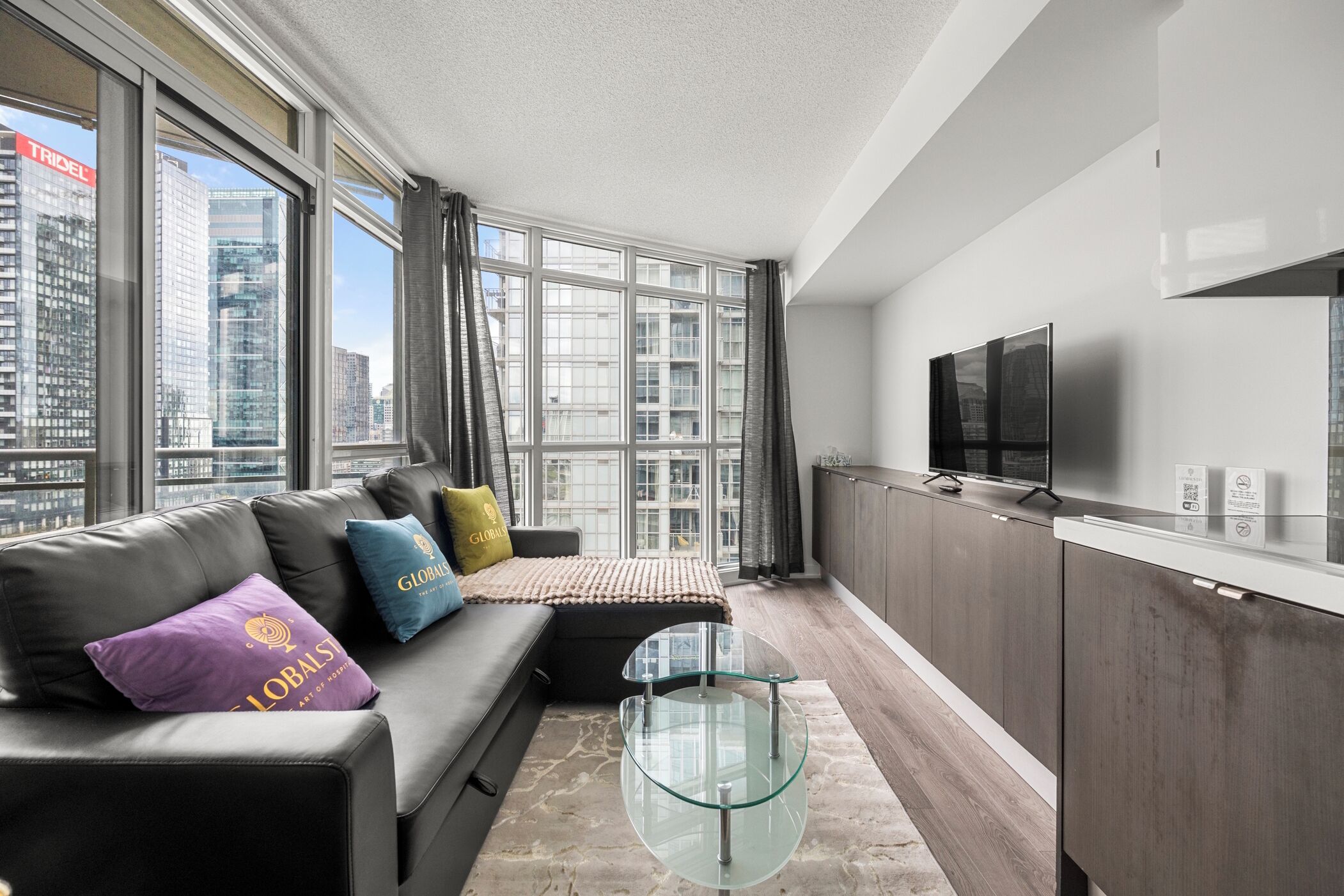A modern living room with a sofa, glass coffee table, and a TV.