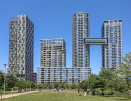 Een modern stadspark met hoge gebouwen op de achtergrond.