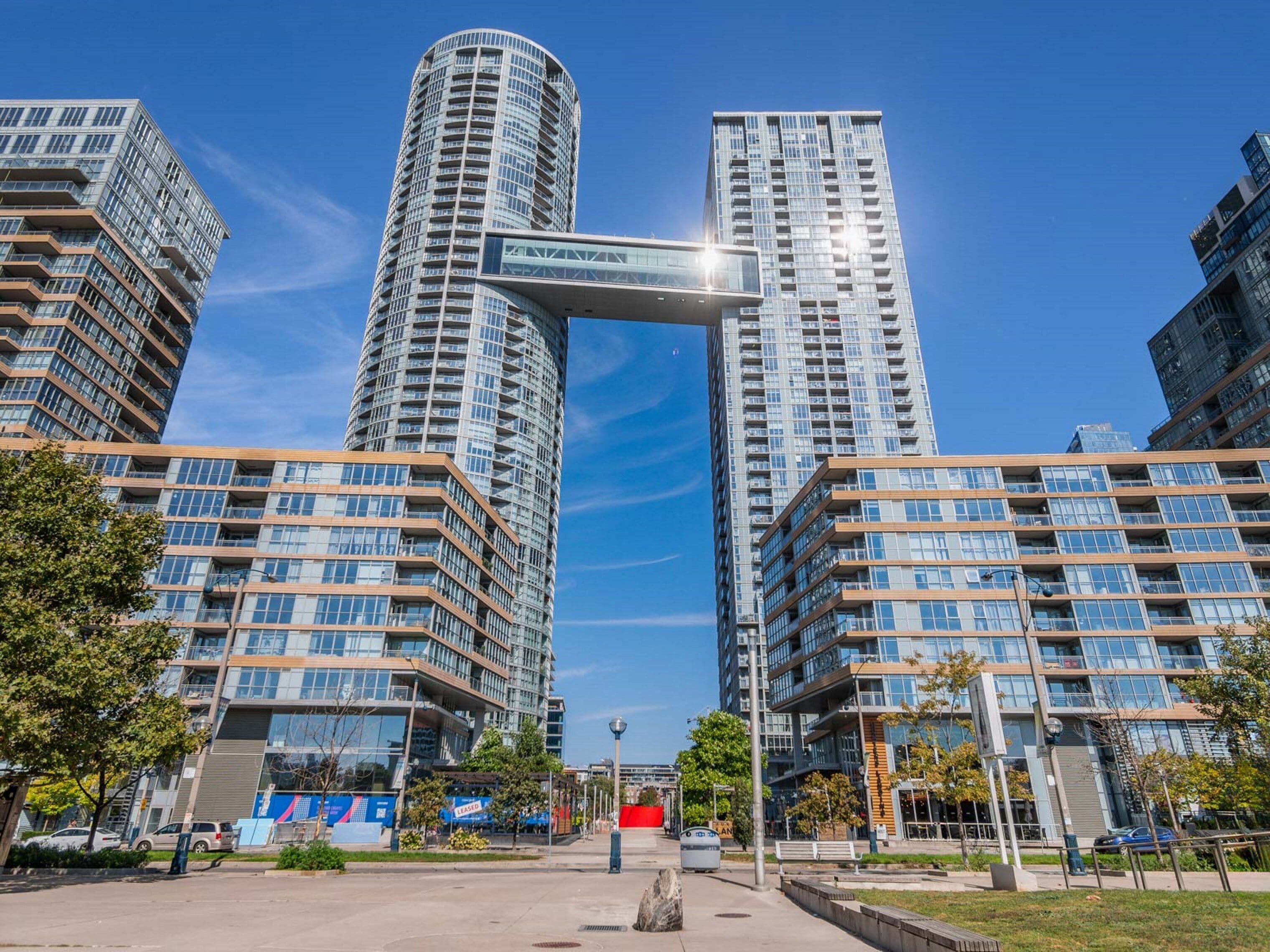 A modern urban area with high-rise buildings, a clear sky, and a pedestrian walkway.