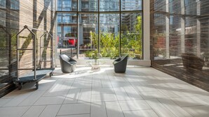 A spacious indoor area with large windows, two modern chairs, a glass table, and a metal cart. - Elegant Downtown Apartments (Toronto)