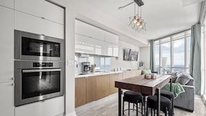 Una cocina moderna con electrodomésticos integrados, una zona de comedor con taburetes de bar y un amplio ventanal con vistas.
