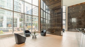 A spacious lobby with large windows, modern seating, and a view of the cityscape. - Elegant Downtown Apartments (Toronto)