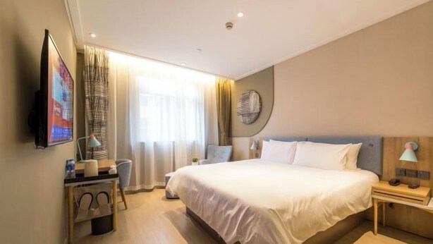 A modern hotel room with a large bed, a desk with a chair, a TV, and a window with curtains. - Home Inn Neo (Shanghai Xujiahui Wanping South Road) (Shanghai)