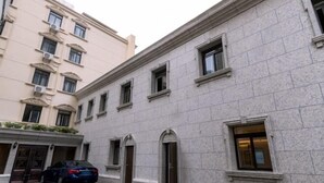 A building with a stone facade, multiple windows, and a car parked in front. - Home Inn Neo (Shanghai Xujiahui Wanping South Road) (Shanghai)