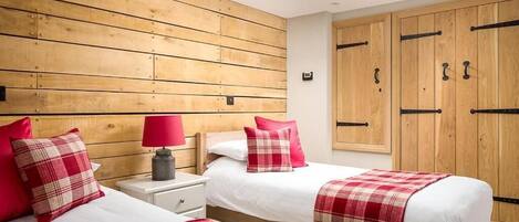A bedroom with two beds, wooden headboard, and a skylight.
