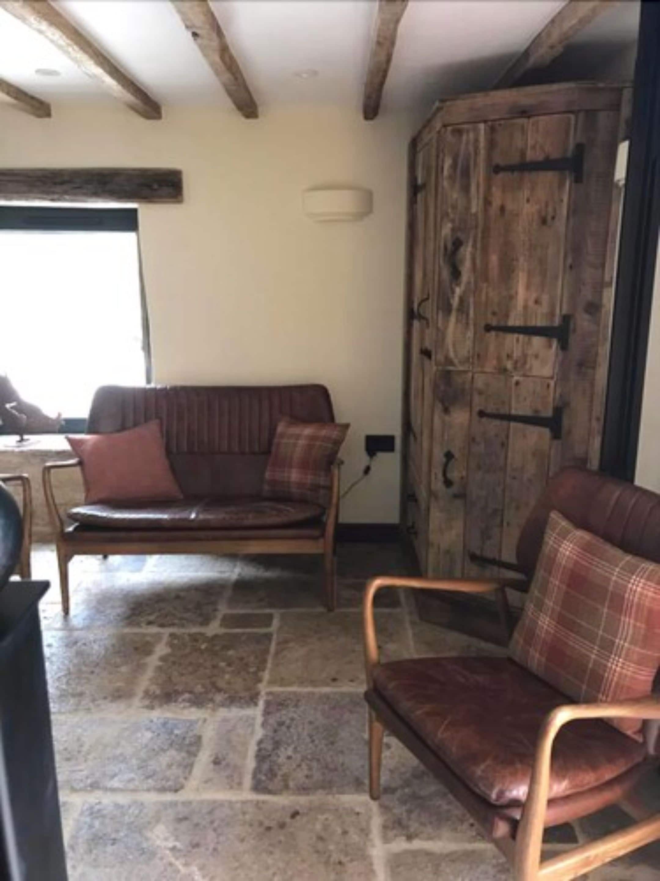 A rustic room with a stone floor, wooden furniture, and a large wooden wardrobe.