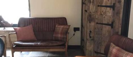 A rustic room with a stone floor, wooden furniture, and a large wooden wardrobe.