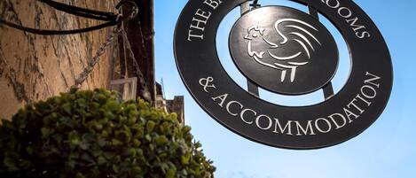 A sign for The Bantam Tea Rooms & Accommodation with a logo featuring a bird and waves.