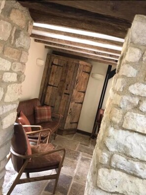 Ein rustikaler Raum mit Steinwänden, einer Holztür und einem Ledersofa.