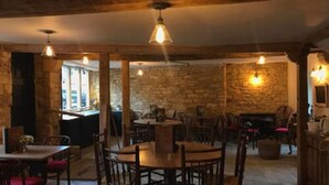 Un coin repas rustique avec des murs en pierre, des meubles en bois et des lampes suspendues.