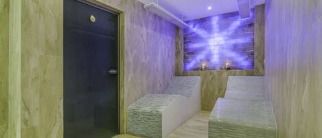 A modern bathroom with marble walls, a glass door, and a purple-lit wall feature.