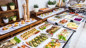 A buffet with various food items and a wooden shelf with potted plants.