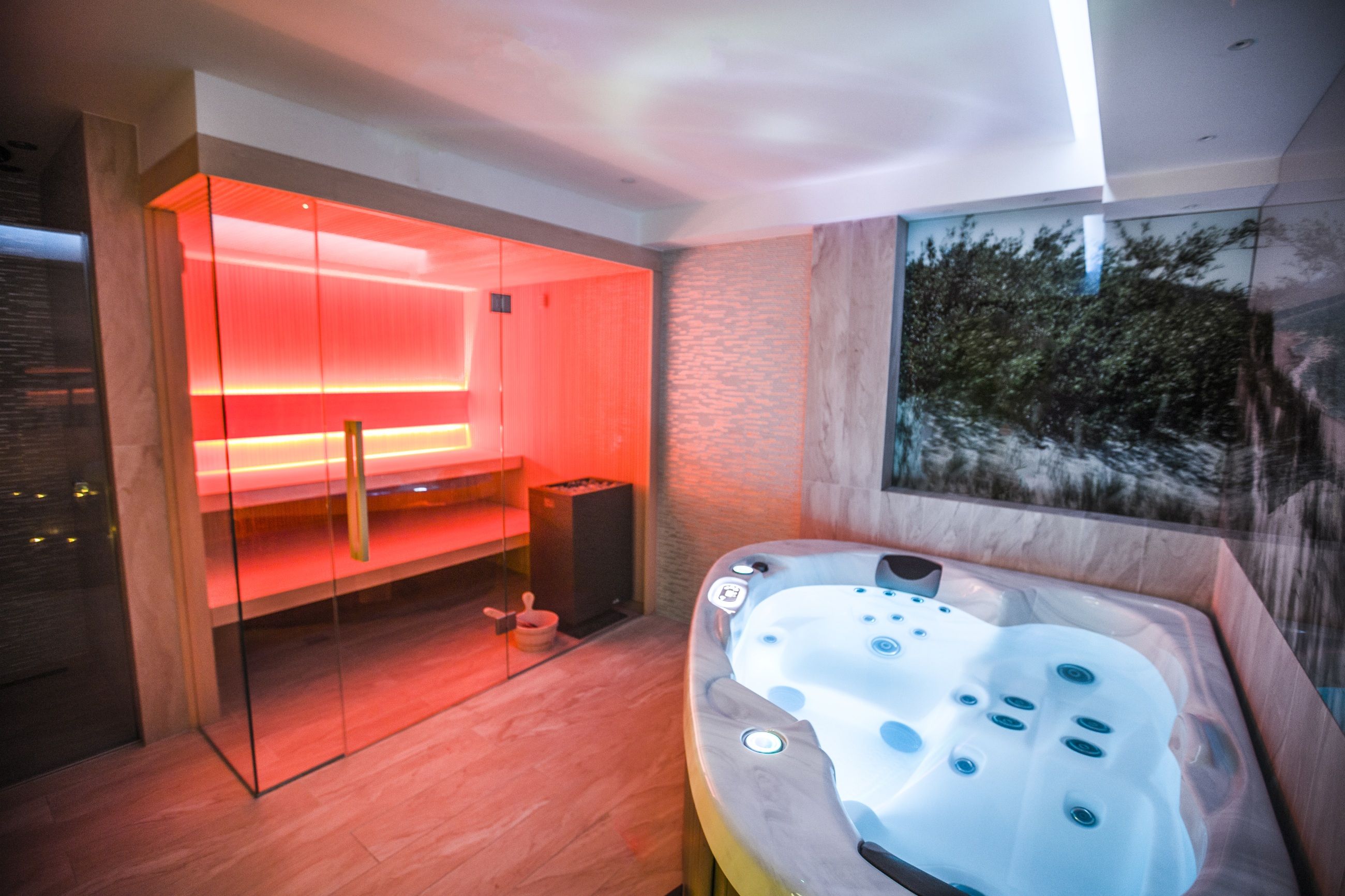 Ein modernes Badezimmer mit einer gläsernen Duschkabine, einer Whirlwanne und Blick auf einen Wald.